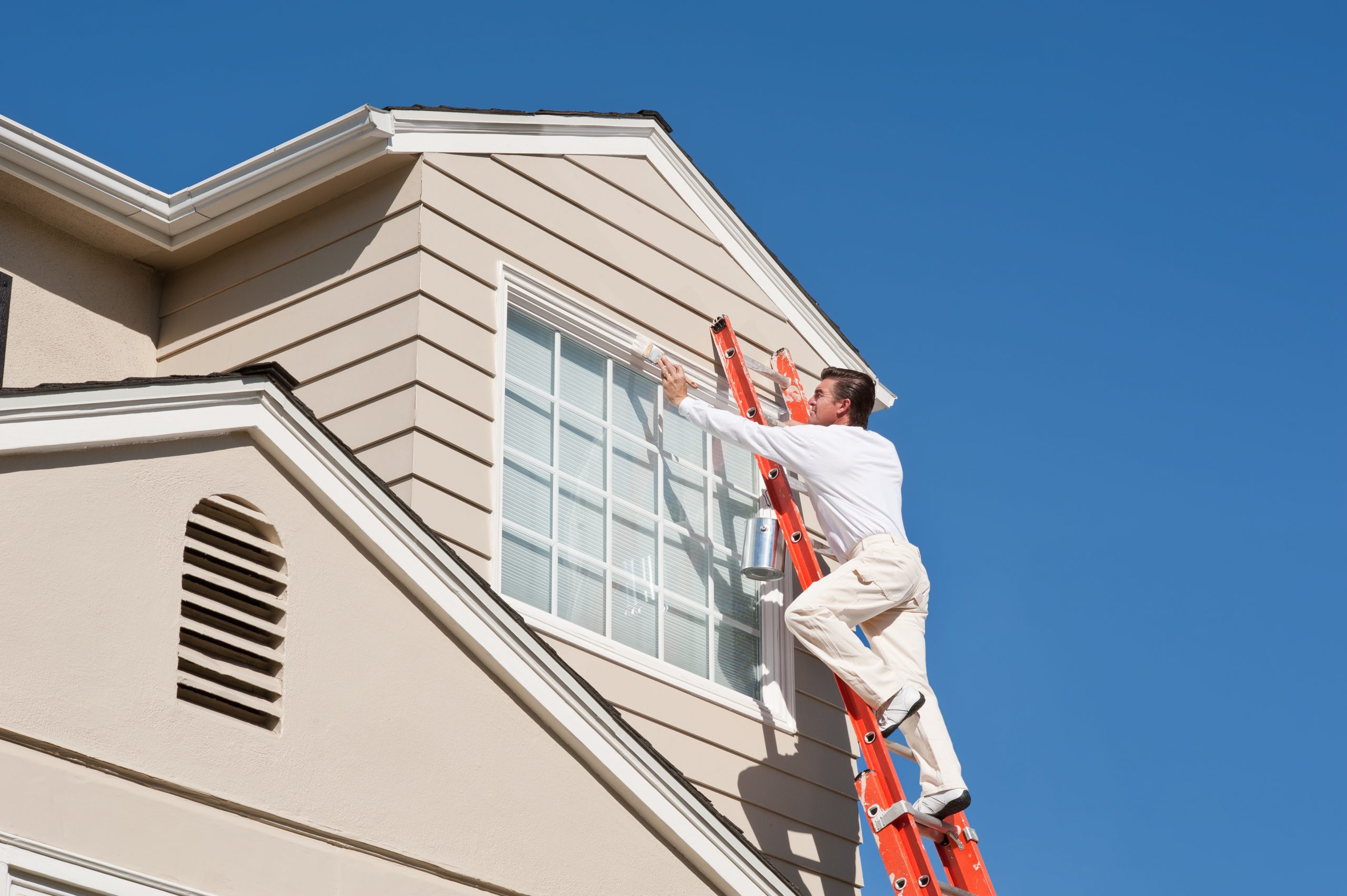 House painter with paint brush painting the trim of a 2nd story window of a Cape Cod Style house.Take a look at our lightbox's of other related images.