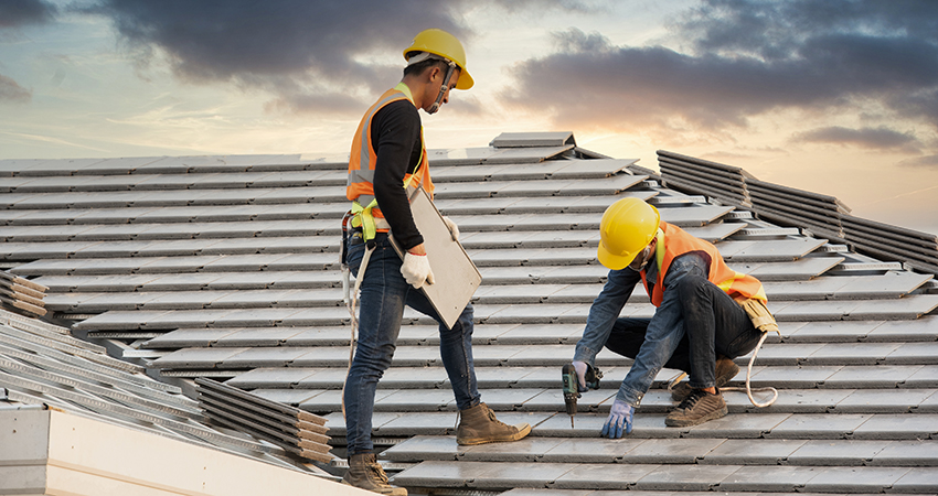 Asian engineer workers install new CPAC roof, roofing tools, electric drill, use on new roof with CPAC roof house construction idea.